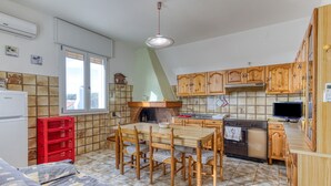 Une cuisine compacte comprenant une table à manger, des chaises, une caisse rouge, un réfrigérateur, des meubles de rangement en bois et un pare-feu en carreaux.
