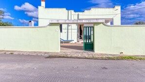 Un bâtiment avec une porte verte, un banc et un ciel bleu clair.
