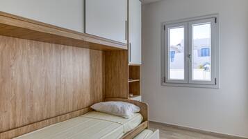 A bedroom with a wooden headboard, a single bed, a window, and a view of buildings outside.