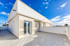 Un bâtiment moderne doté d’un toit plat, de grandes portes-fenêtres coulissantes et d’une terrasse carrelée.