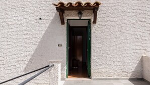 A building entrance with a white textured wall, a wooden overhang, and a tiled floor. - Pet-Friendly Villa 'Rosa' with Sea View & Terraces (Licata)