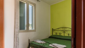 A bedroom with a bed, a window, and a green wall. - Pet-Friendly Villa 'Rosa' with Sea View & Terraces (Licata)