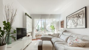 Un salon moderne avec un canapé, un téléviseur, une table basse et une plante en pot.