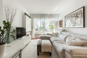 A modern living room with a sofa, a TV, a coffee table, and a potted plant.