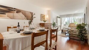 Un coin repas avec une table dressée pour quatre personnes, un buffet en bois et un canapé en arrière-plan.