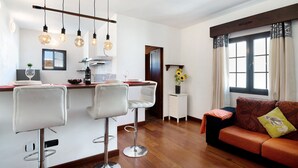 A modern kitchen with bar stools, a dining table, and pendant lighting.
