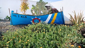 A blue sign with 'SOL Y MAR' and a ship's wheel symbol, surrounded by cacti and desert plants.