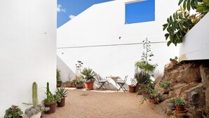 A courtyard with potted plants, a table, and chairs.