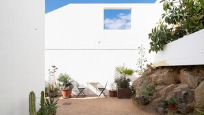 Un patio con plantas en macetas, una mesa y sillas.