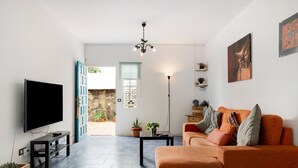 Una sala de estar con televisor, sofá y candelabro.