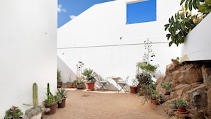 A courtyard with potted plants, a table, and chairs. - Casa Sol Y Mar: Sea Views, Private Pool & Wi-Fi in Lanzarote (Tías)