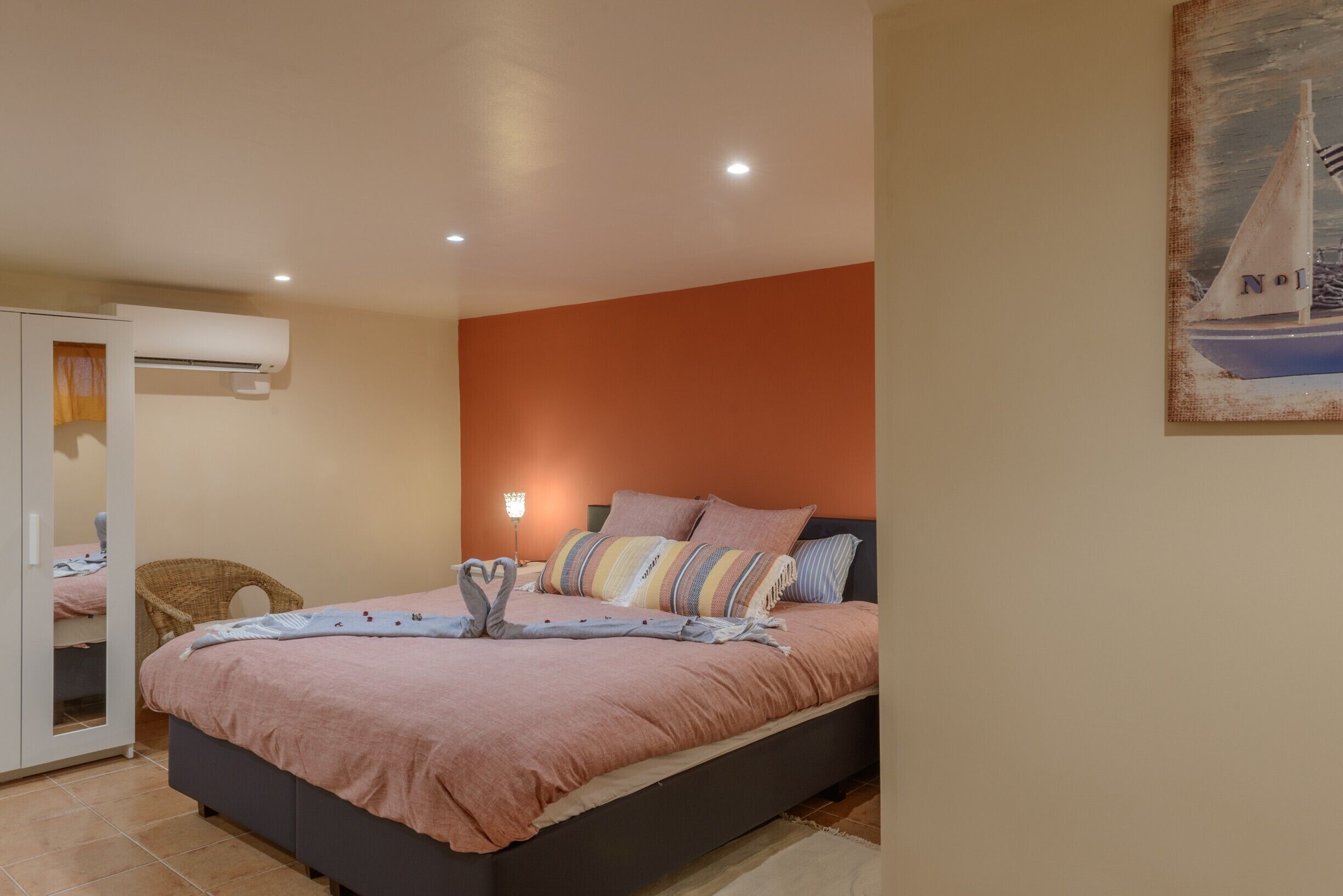 Une chambre à coucher avec un lit, une armoire, un miroir et un tableau accroché au mur.