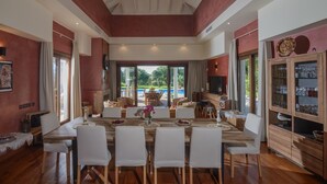 Uma sala de jantar espaçosa com uma mesa grande, cadeiras e vista para uma piscina.