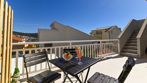 A balcony with a table and chairs, a glass of drink, and a small garden gnome.