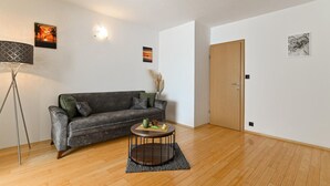 A living room with a grey sofa, a round coffee table, a floor lamp, and a door.