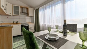 A modern kitchen with white cabinets, a stove, and a dining area with a table set for two.