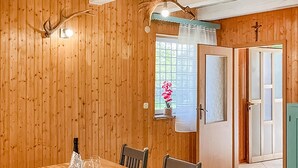 Un interior de madera con una mesa de comedor, sillas, una botella y copas de vino.