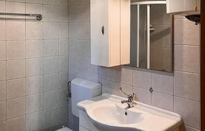 Casa de banho com lavatório branco, sanita e armário.