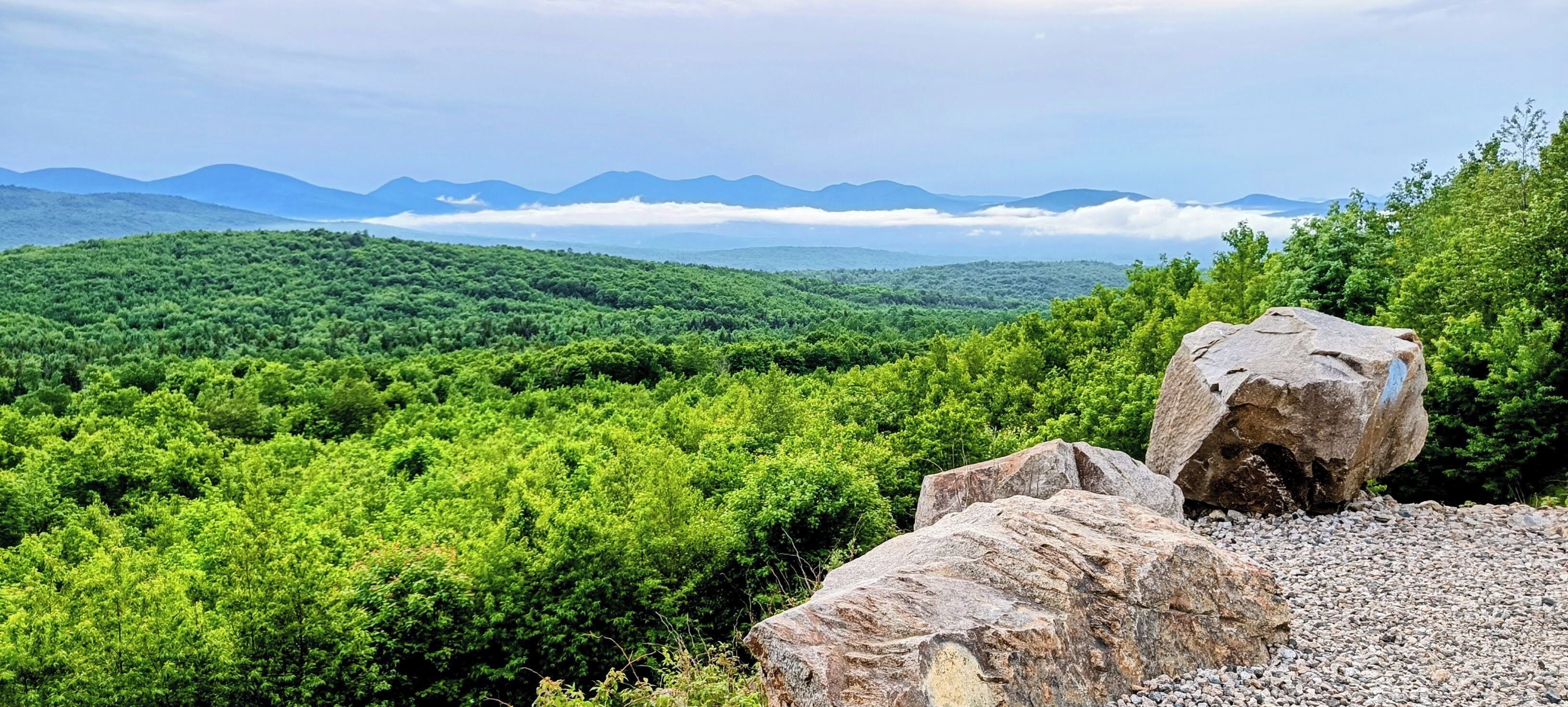 A mountainous landscape with dense green vegetation and a prominent rock formation.