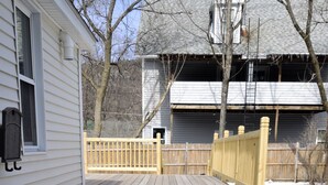 A wooden deck with a wooden fence and a house in the background. - Grand Trunk Cottage - a home for all seasons! (Gorham)