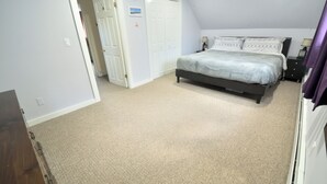 A bedroom with a bed, a nightstand, and a closet. - Grand Trunk Cottage - a home for all seasons! (Gorham)