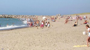 Une plage bondée où l’on voit des gens se promener et nager.