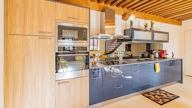 Una cocina moderna con armarios de madera, electrodomésticos de acero inoxidable y una isla central.