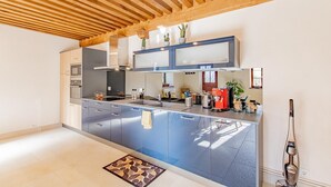 Una cocina moderna con techo de madera, electrodomésticos integrados y una isla central.
