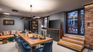 A modern dining area with a wooden table, blue chairs, and a chandelier.