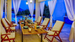 An outdoor dining area with a wooden table set for six, surrounded by red and white chairs. - Gorgeous home in Gornji Muc (Gornji Muc)