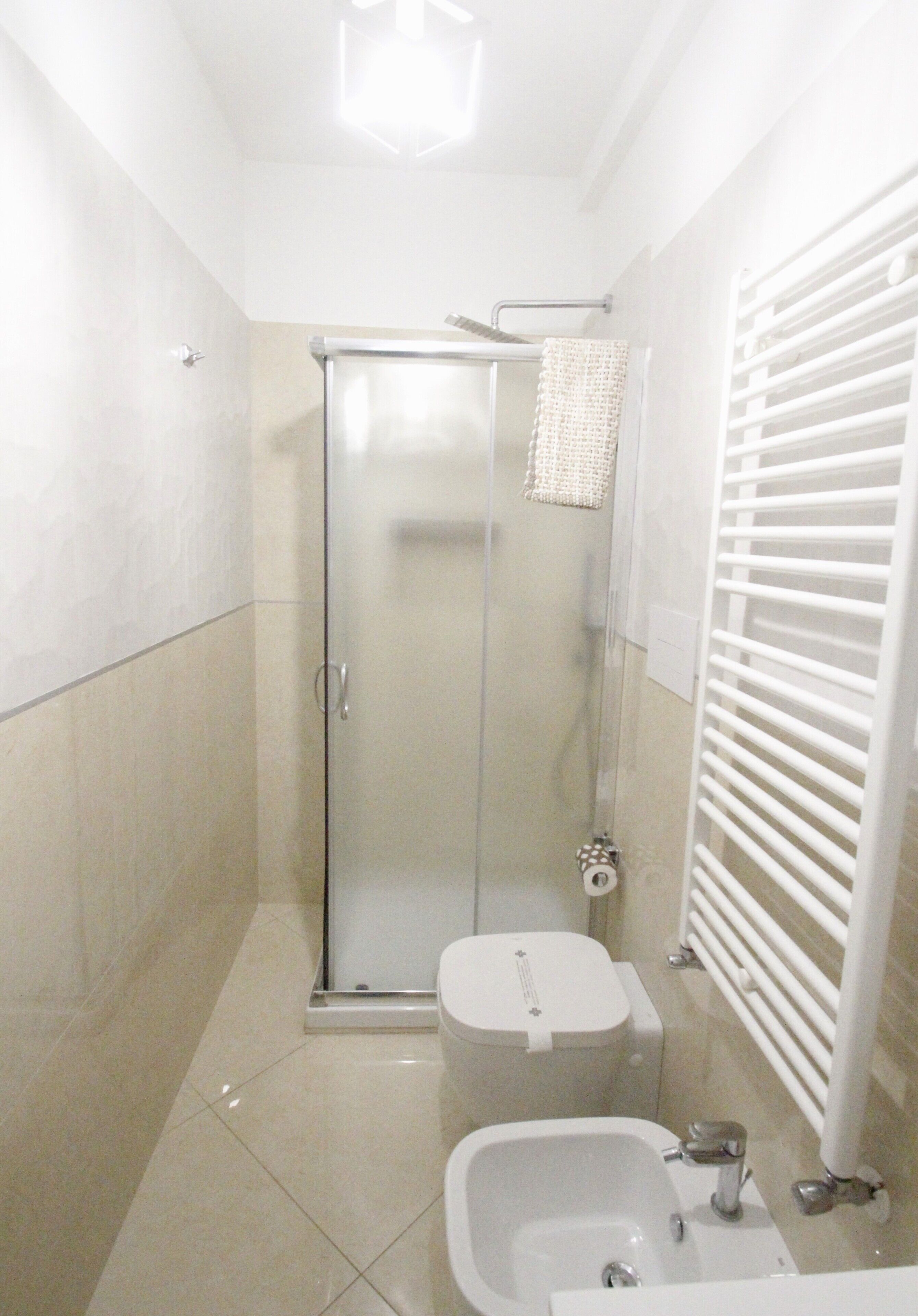 A small, modern bathroom with a glass shower enclosure, a toilet, a bidet, and a sink.
