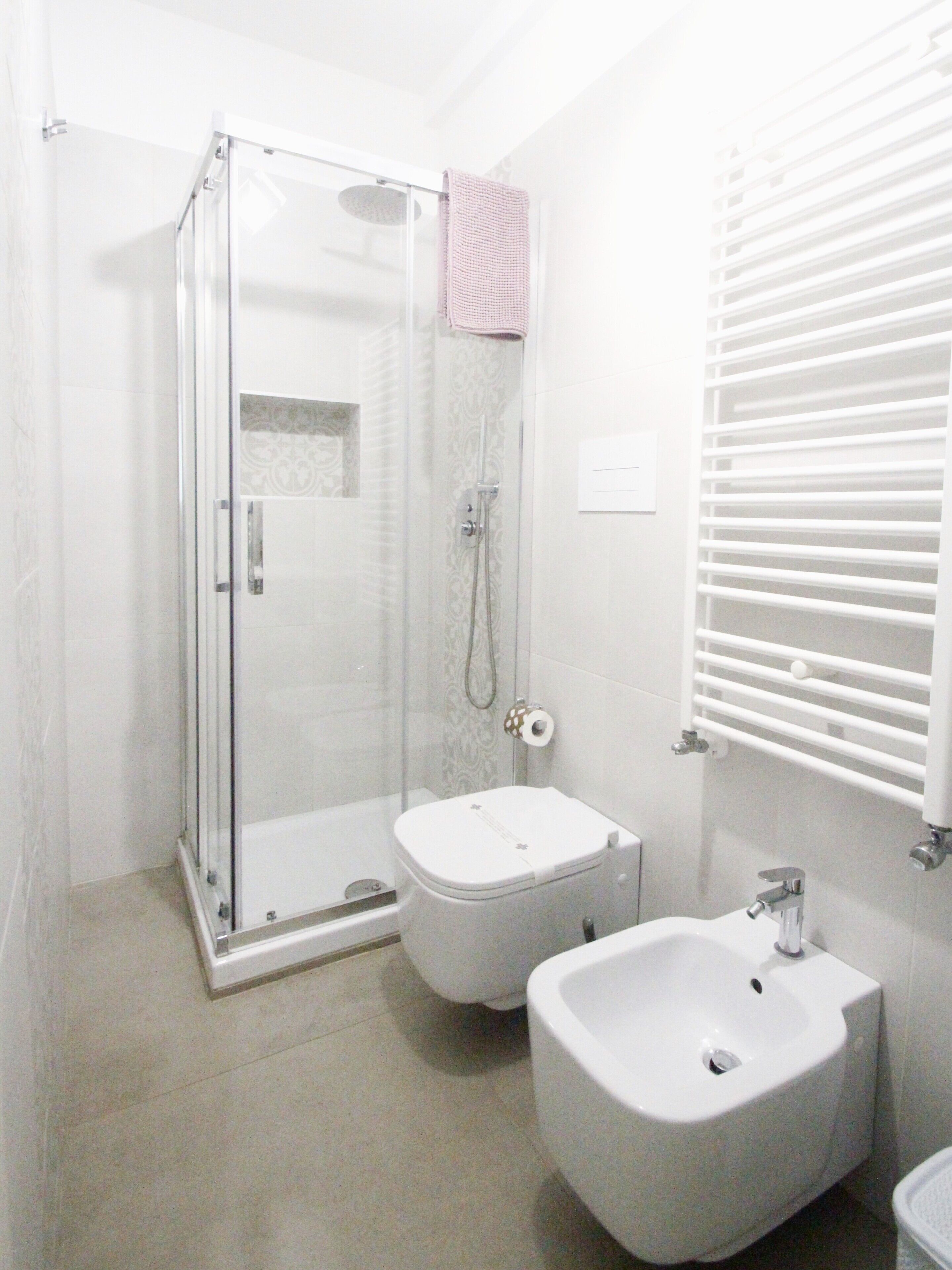 A bathroom with a glass-enclosed shower, a toilet, and a bidet.