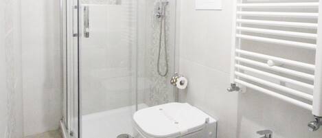 A bathroom with a glass-enclosed shower, a toilet, and a bidet.