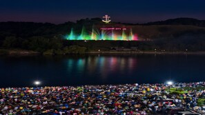 Ampio evento all'aperto con un palco e luci colorate sullo sfondo.