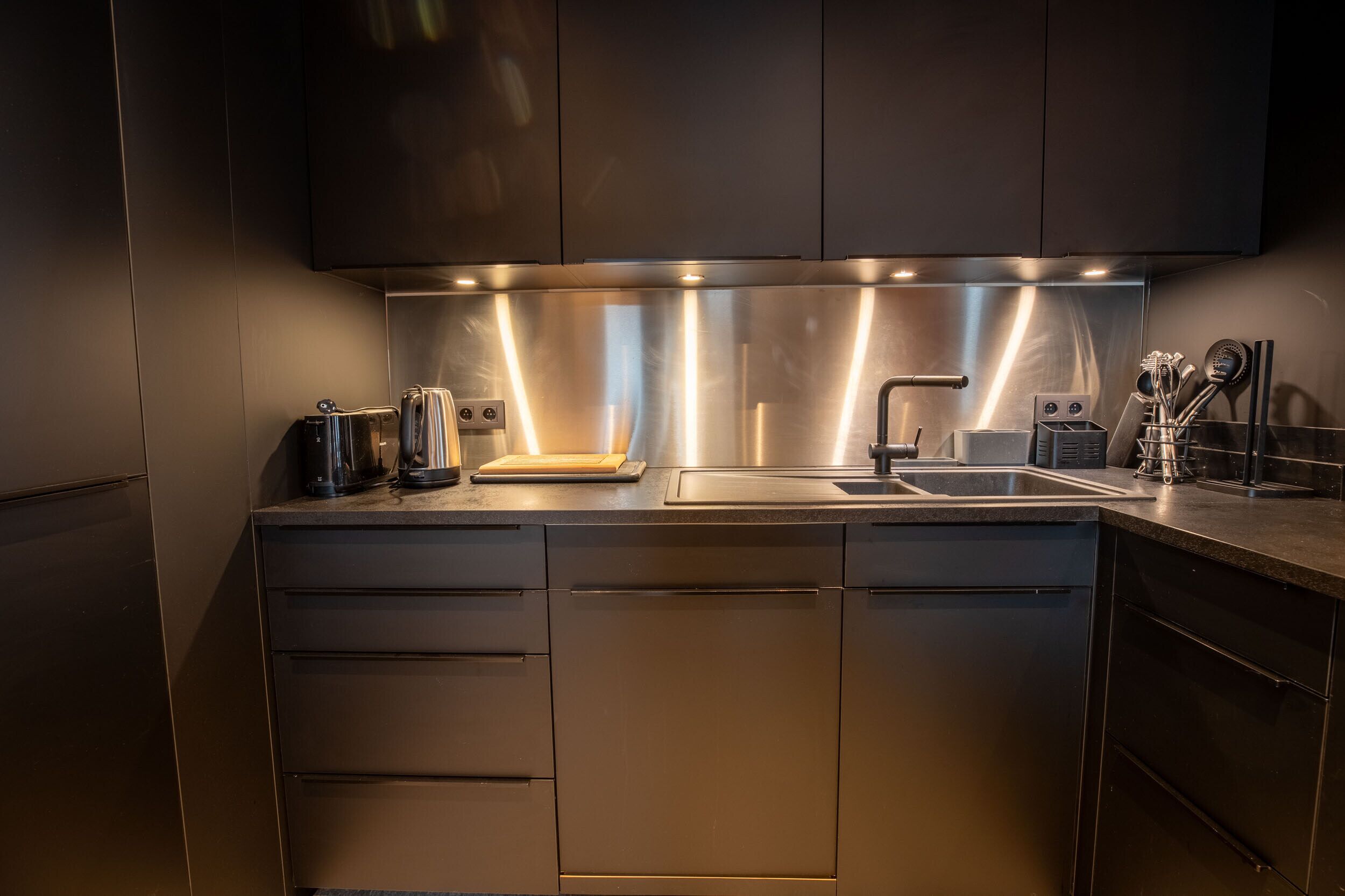 A modern kitchen with stainless steel appliances, a double sink, and a built-in oven.