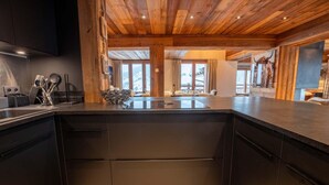 A modern kitchen with dark cabinetry, a wooden ceiling, and a large island.