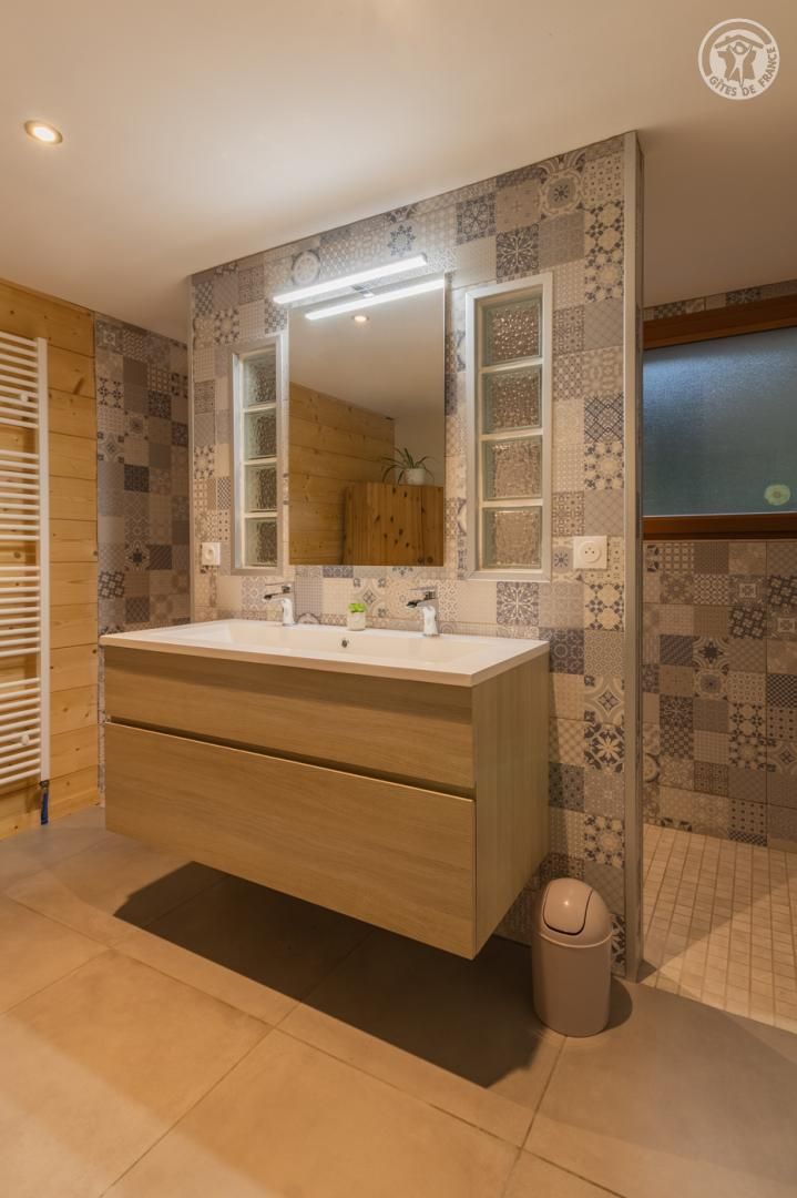 Un bagno con un ampio lavabo, uno specchio e piastrelle decorate.