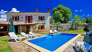 A pool area with lounge chairs, a stone pool, and a stone building with red shutters. - Lovely home in Tinjan with WiFi (Tinjan)