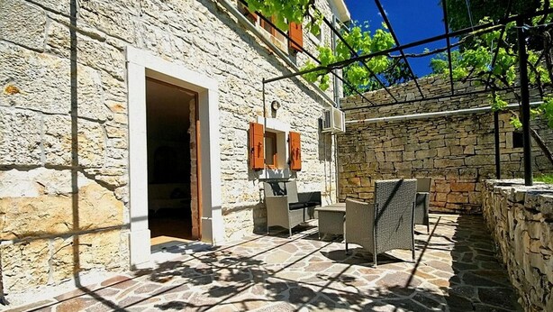 A stone building with a patio area featuring outdoor furniture and a stone floor. - Lovely home in Tinjan with WiFi (Tinjan)