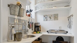 Een keuken met een wit aanrecht, een koffiezetapparaat, een waterkoker en een kist met fruit, gelabeld 'FRUTAS ESPANA'.