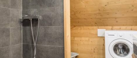Ein kleines Badezimmer mit Dusche, Waschmaschine und Toilette.