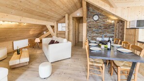 A cozy wooden interior with a dining area, white sofa, and a clock on the wall. - LE Sapi - Albiez-montrond (ALBIEZ-MONTROND)
