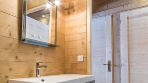 A wooden cabin bathroom with a mirror, sink, and cabinets. - LE Sapi - Albiez-montrond (ALBIEZ-MONTROND)