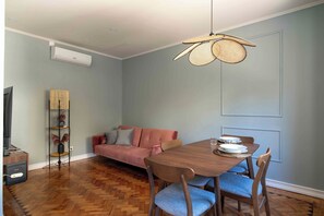 Relax in this stylish living space with a dining area, featuring a dining table, sofa, and TV.