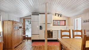 A cozy cabin interior with a wooden dining table, chairs, a kitchen with a stove, and a large window. - Stunning home in Silkeborg with WiFi (Silkeborg)