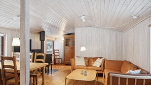 A cozy cabin interior with wooden walls, a sofa, a dining table, and chairs. - Stunning home in Silkeborg with WiFi (Silkeborg)