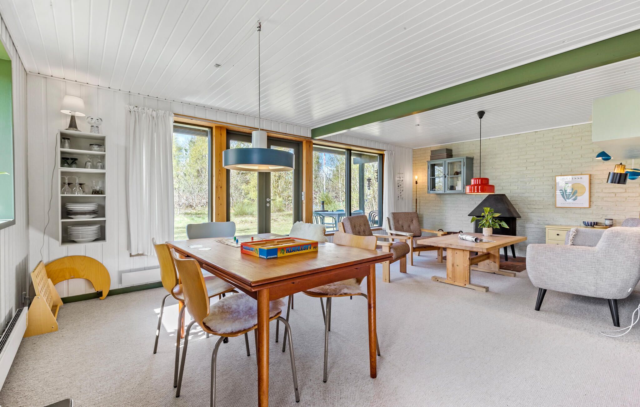 A modern living room with a wooden dining table, comfortable seating, a fireplace, and a view of the outdoors.