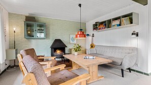A cozy living room with a fireplace, wooden furniture, and a bookshelf. - 3 bedroom beautiful home in ørsted (Ørsted)