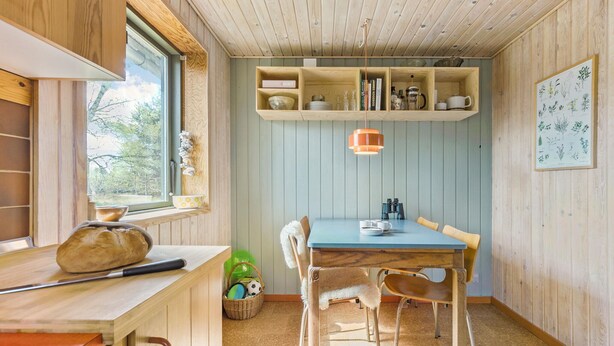 A cozy dining area with a wooden table and chairs, a hanging pendant light, and a window with a view of trees. - 3 bedroom beautiful home in ørsted (Ørsted)