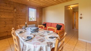 A wooden cabin with a dining area featuring a round table, chairs, and a red sofa. - O'mikely - LE Dingo - Albiez Montrond (ALBIEZ MONTROND)